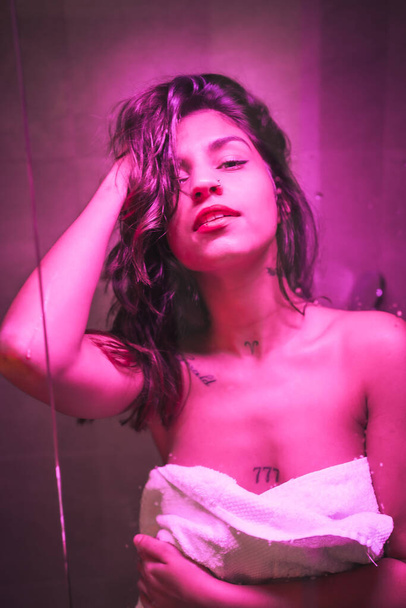 Styl życia, sexy brunetka kaukaska dziewczyna z ręcznikiem na końcu prysznica z zmysłowym wyglądem, z różowym led light - Zdjęcie, obraz