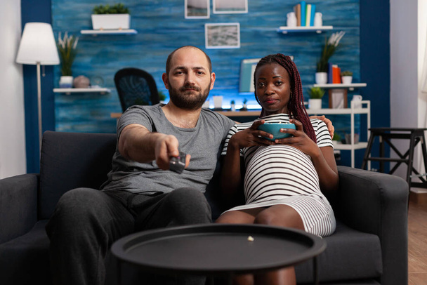 Těhotné mezirasový pár dívá na kameru sledování televize - Fotografie, Obrázek