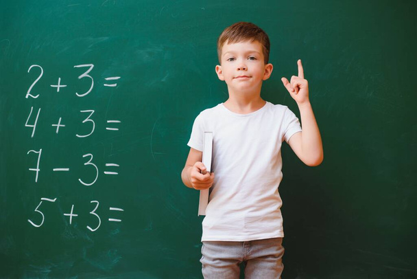 Back to school concept. School child in class. Happy kid against green blackboard. Smart child in classroom. Idea and education concept - Фото, изображение