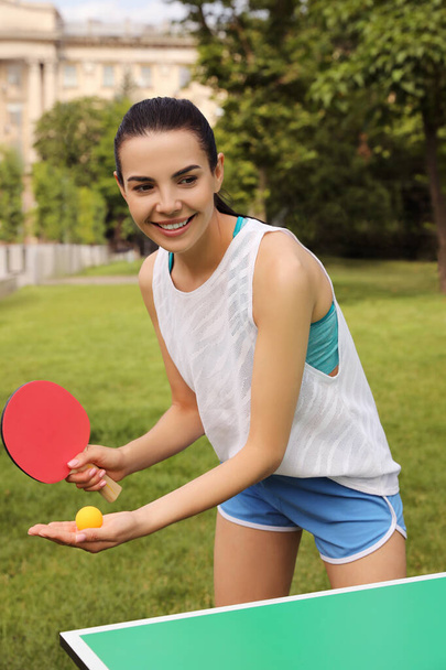 Young woman playing ping pong outdoors on summer day - Foto, imagen