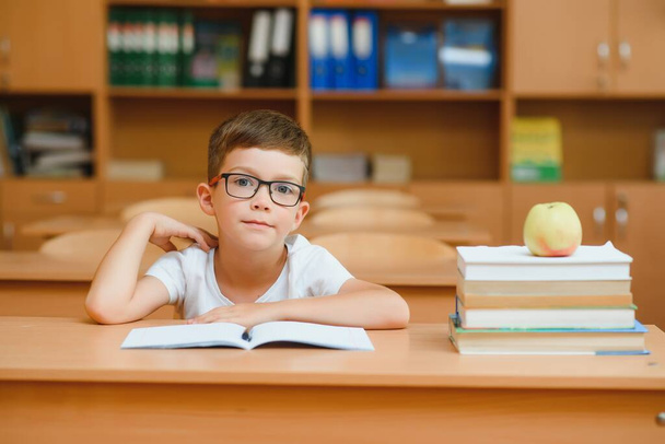 Elementary school boy at classroom desk trying to find new ideas for schoolwork. - Foto, immagini