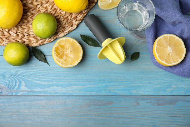 Citrus reamer, fresh lemons and limes on light blue wooden table, flat lay. Space for text - Foto, immagini