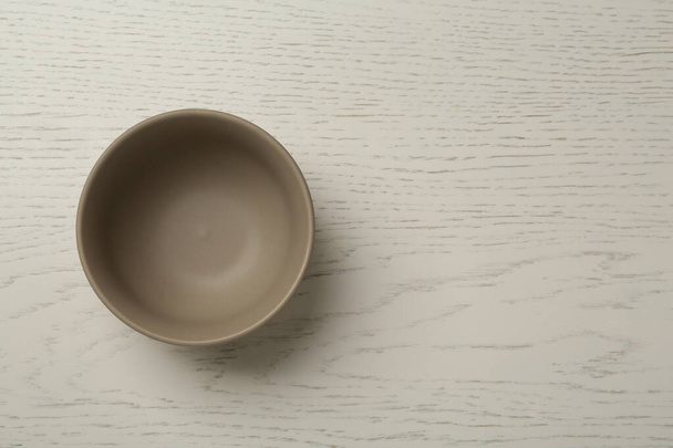 Stylish empty ceramic bowl on white wooden table, top view and space for text. Cooking utensil - Foto, Imagem