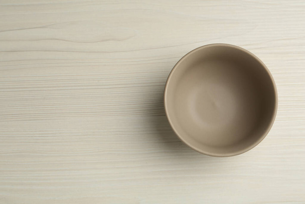Stylish empty ceramic bowl on white wooden table, top view and space for text. Cooking utensil - Photo, image