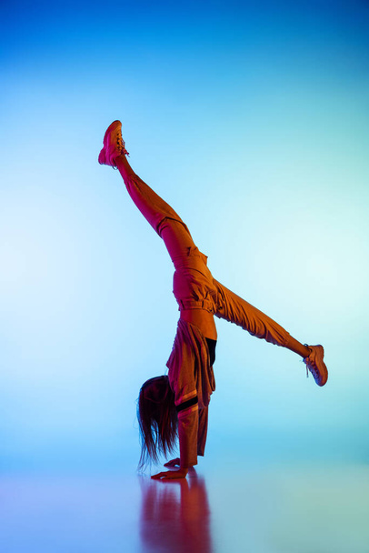 Young sportive girl dancing break dance alone isolated on colorful background at dance hall in neon light. Youth culture, movement, style and fashion, action. - Foto, Bild
