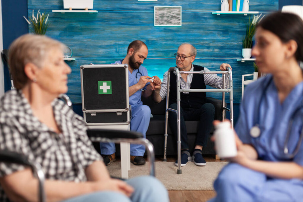 Sosiaaliavustaja keskustelemassa terveydenhuollon lääkityksestä iäkkäiden vammaisten eläkeläisten kanssa - Valokuva, kuva