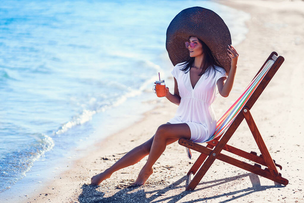 Pretty woman in big straw hat relaxing on a lounger beach and drinks refreshing juice. summer vacation concept - Fotoğraf, Görsel