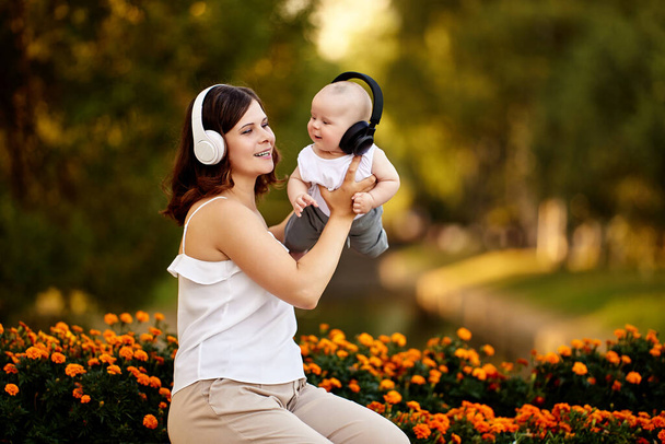 Wireless headphones for young woman and her baby during walk in nature on summer evening. - Photo, Image