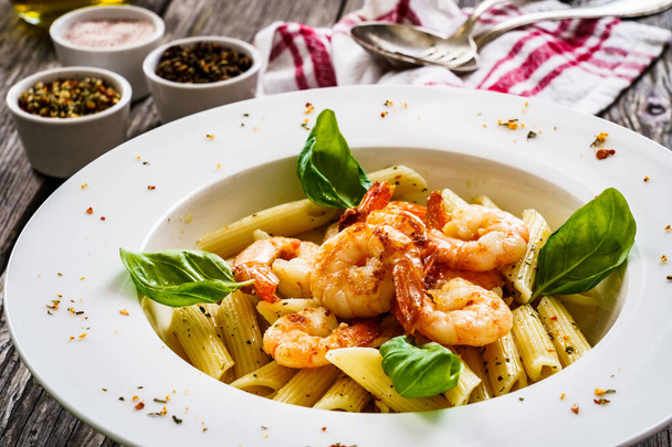 Penne with fried prawns on wooden background - Foto, imagen