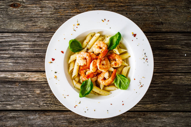 Penne with fried prawns on wooden background - Photo, Image