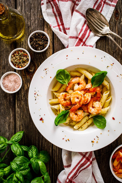 Penne with fried prawns on wooden background - Foto, afbeelding