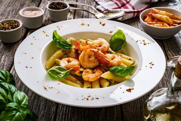 Penne with fried prawns on wooden background - Foto, Imagen