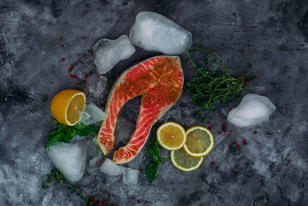 Syrový lososí steak s bylinkami, ledem a citronem na šedém pozadí - Fotografie, Obrázek