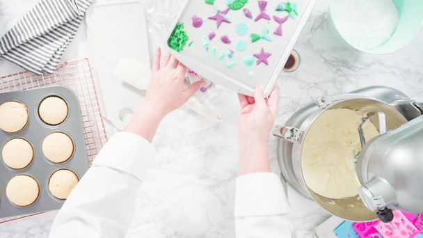 Plat gelegd. Stap voor stap. Mengen van ingrediënten in de keuken mixer om boterroom glazuur te maken voor zeemeermin thema vanille cupcakes. - Foto, afbeelding