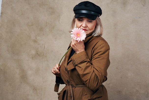 elegante anciana en abrigo sosteniendo una flor de moda - Foto, imagen