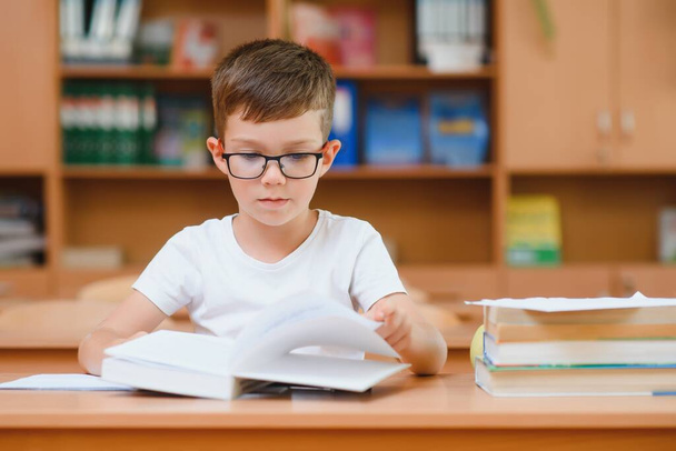 Elementary school boy at classroom desk trying to find new ideas for schoolwork. - Foto, immagini