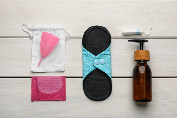 Cloth menstrual pad and other female hygiene products on white wooden table, flat lay - 写真・画像