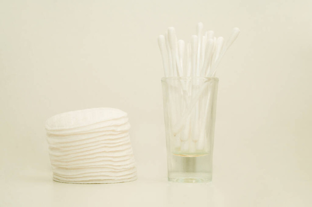 Detailní záběr na hromadu vatových podložek a vatových tamponů ve skleněném kelímku. Bílé pozadí. - Fotografie, Obrázek