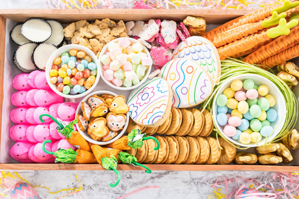 Samenstellen van charcuterie board met Pasen snoepjes, koekjes en marshmallows. - Foto, afbeelding