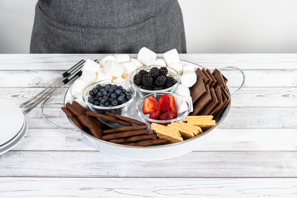 Arranging fruit s'mores charcuterie board on a white tray. - Photo, Image