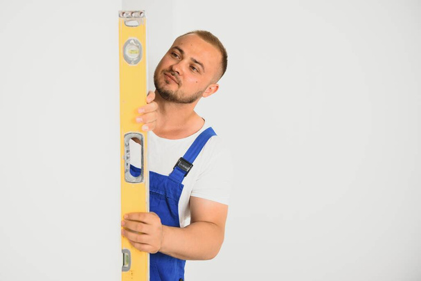 Repairman check the evenness of the wall using a spirit level. - Фото, изображение
