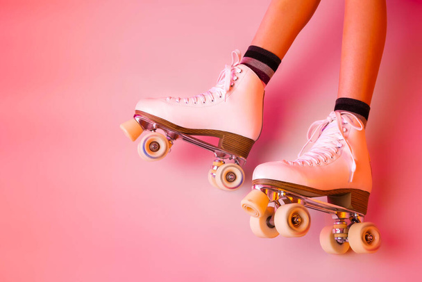 Retro classic white leather roller skates and girls legs - sports equipment and recreation. Pastel pink background. Layout with free copy space. - Foto, immagini