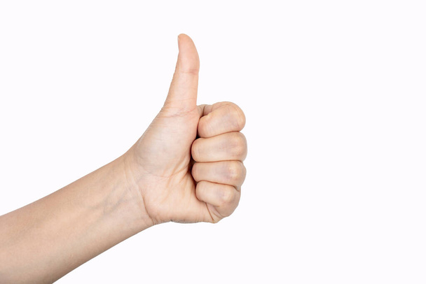 Close-up van vrouwelijke hand tonen duimen omhoog teken tegen witte achtergrond. - Foto, afbeelding