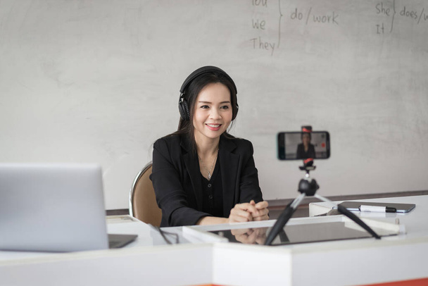 Aikuinen aasialainen naispuolinen college opettaja opettaa verkossa videoneuvottelun kautta opiskelijoille kotona. Hymyilevä aasialainen naisopettaja, jolla on videopuhelu opiskelijoiden kanssa. - Valokuva, kuva