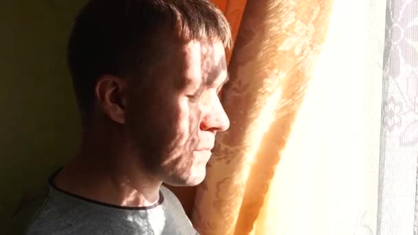 Mies laittaa FFP2 hengityssuojain verhottu ikkuna kirkas luonnollinen auringonvalo - Materiaali, video