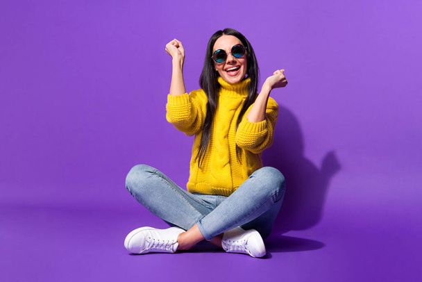 Full size portrait of astonished lady sit fists up open mouth smile yeah isolated on purple color background - Photo, image