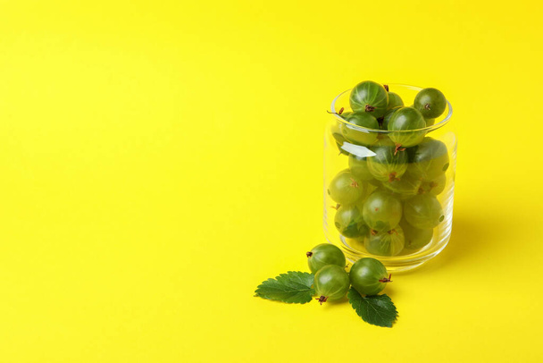 Jar of ripe gooseberry on yellow background - Photo, Image