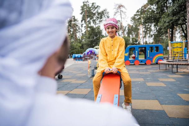 Mosolygó fiú időt tölt muszlim apa a játszótéren a szabadban - Fotó, kép