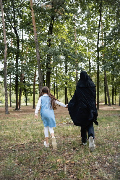 Vissza kilátás az arab anya és lánya fut a parkban  - Fotó, kép