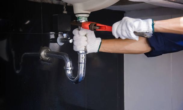 Loodgieter bevestiging witte gootsteen pijp met verstelbare moersleutel. - Foto, afbeelding
