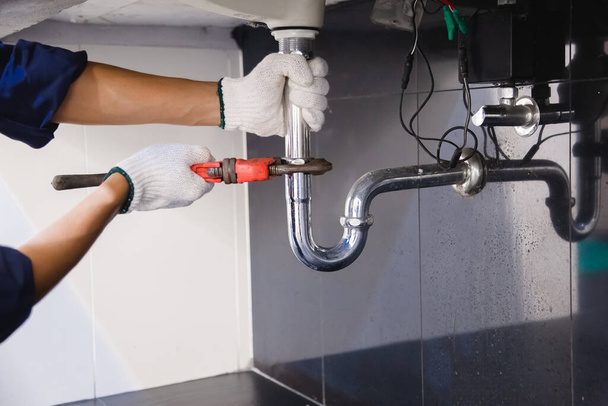 Plumber fixing white sink pipe with adjustable wrench. - Fotoğraf, Görsel