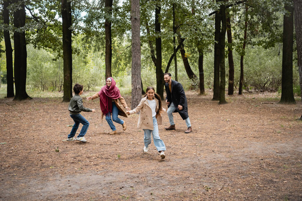Boldog muszlim lány játszik a szülőkkel és a testvérrel a parkban  - Fotó, kép