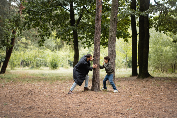 Arabian ojciec bawi się z synem w pobliżu drzewa w parku  - Zdjęcie, obraz