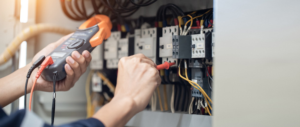 電気工事士は電気キャビネットの制御で電圧と電力線の電流を測定し、コンセプトは、電気システムの動作を確認します . - 写真・画像