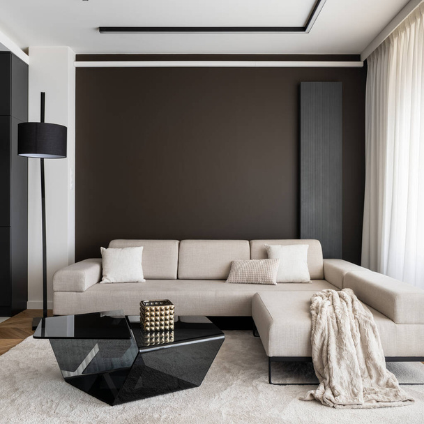 Stylish big, beige, corner sofa, modern, black coffee table on beige carpet in elegant living room - Foto, Imagen