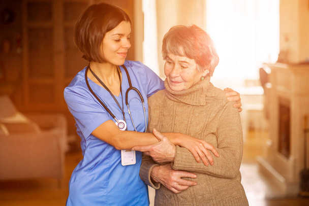 Een jonge verpleegster toont zorg en professionaliteit in relatie tot een oudere vrouw. - Foto, afbeelding