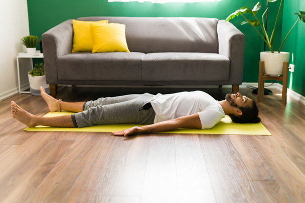 Hispánec se zavřenýma očima dělá dechová cvičení a relaxaci při cvičení savasana  - Fotografie, Obrázek