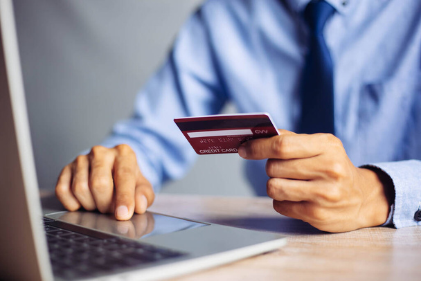 Online-Zahlung: Mann hält Kreditkarte in den Händen und nutzt Smartphone für Online-Einkäufe - Foto, Bild
