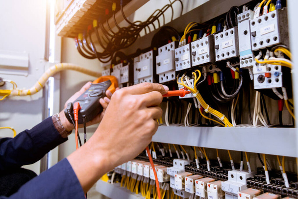 Mediciones de electricista con corriente de prueba de multímetro eléctrica en el panel de control. - Foto, imagen