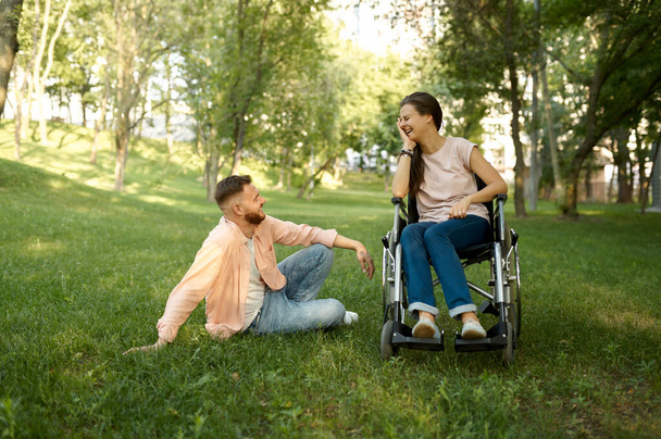 Family couple with wheelchair leisures in park - Фото, зображення