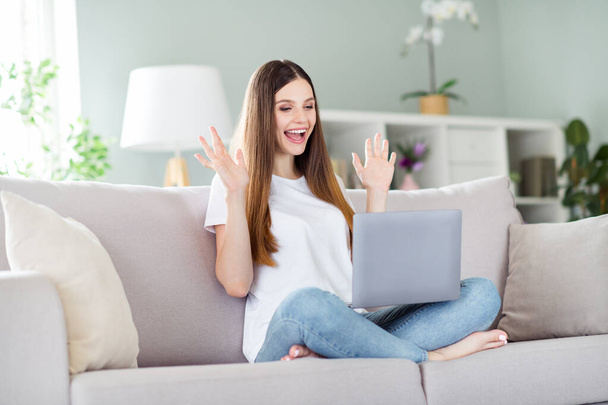 Portrait of attractive cheerful lucky girl sitting on divan using laptop having fun at home living room indoors - Foto, Imagem