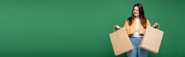 Boldog nő túlsúlyos gazdaság bevásárló táskák elszigetelt zöld, banner  - Fotó, kép