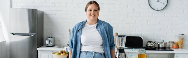 Mulher positiva com excesso de peso em pé perto de comida na cozinha, banner  - Foto, Imagem