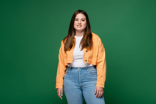 Cheerful plus size woman looking at camera isolated on green  - Foto, afbeelding