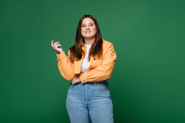 Young plus size woman smiling at camera isolated on green  - Foto, Bild