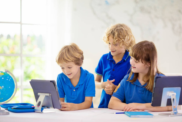 Çevrimiçi uzaktan öğrenme. Bilgisayarlı okul çocukları öğretmen ve sınıf grubuyla görüntülü konuşma yapıyorlar. Çocuk evden ders çalışıyor. Karantina ve koronavirüs salgını sırasında evde eğitim. - Fotoğraf, Görsel
